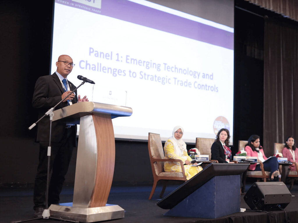 A man speaks from a podium next to a panel